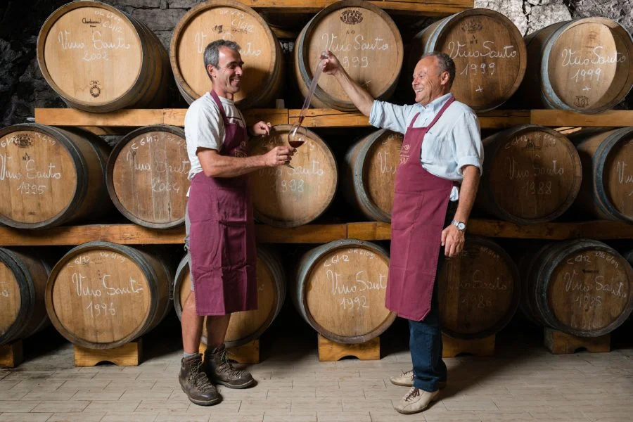 trentino-pisoni-due-persone-di-fronte-a-botti-di-vino.webp